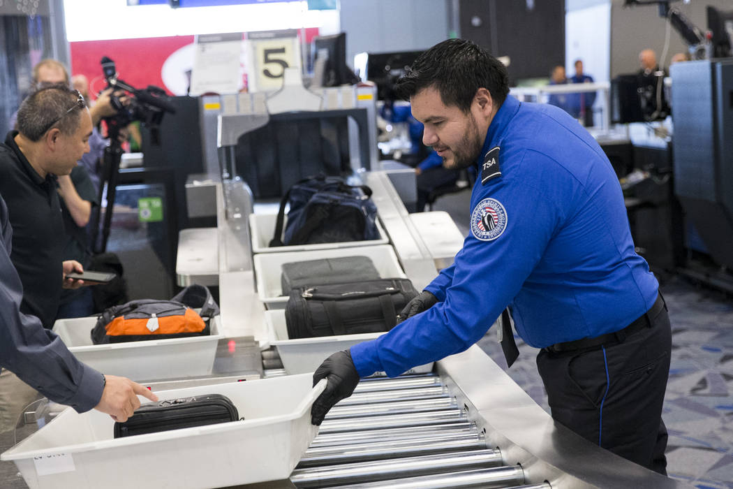 Transportation Security Administration agent Eduardo Puga, right, assists a passenger in one of the new automated screening lanes at McCarran International Airport Terminal 1 in Las Vegas, on Thur ...