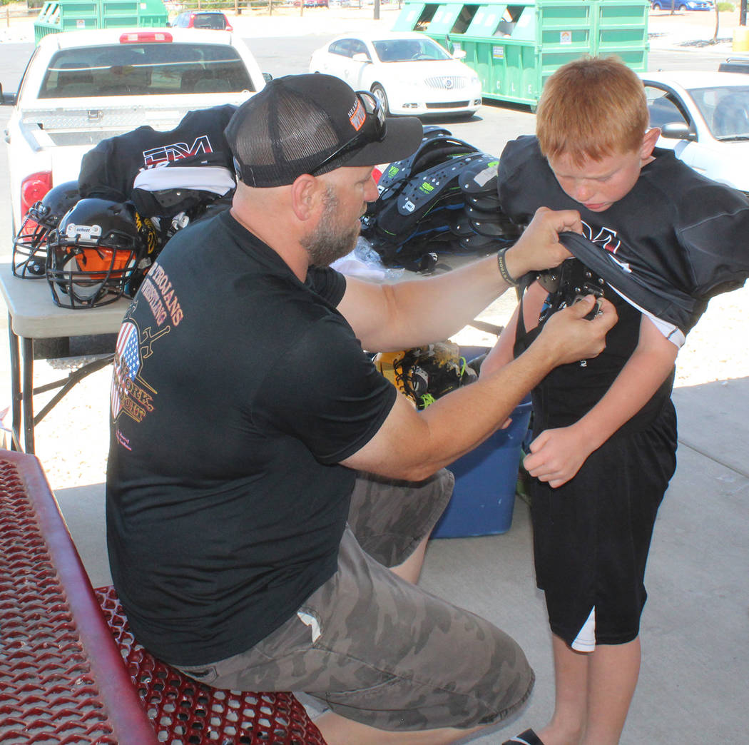 Tom Rysinski/Pahrump Valley Times Chance Brown, 9, gets some help sizing football equipment from Pahrump Youth Sports President Johnny O'Neal on Saturday during football sign-ups at the Sonic on R ...