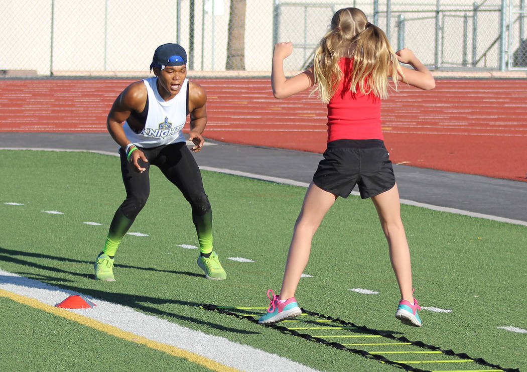 Tom Rysinski/Pahrump Valley Times Dominique Maloy shouts encouragement to McKenna Cunningham, 10, during "A Youth Sports Experience" session Sunday on the football field at Pahrump Valley High School.