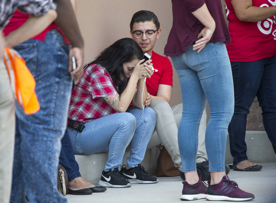 Unidentified Target department store employees comfort each other as Las Vegas police investigate an officer-involved shooting at a shopping complex near Blue Diamond Road and Arville Street in La ...