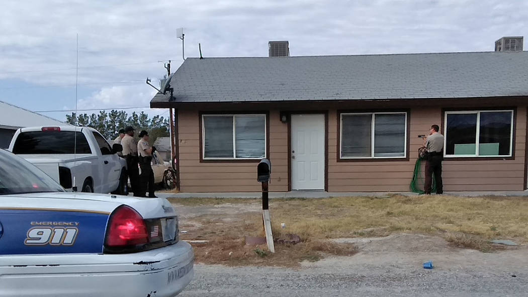 Selwyn Harris/Pahrump Valley Times A Nye County Sheriff's Deputy with a drawn gun stands near the entrance of the Galaxy Avenue home, as additional deputies assemble along the opposite side, as th ...