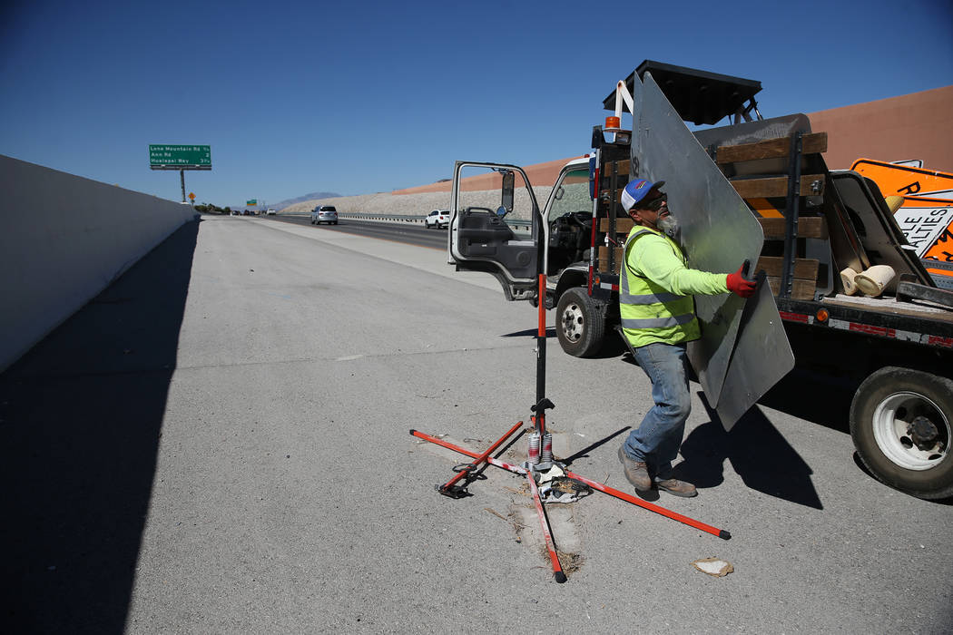 Cesar Escobar, traffic control supervisor for Las Vegas Paving Corporation,  removes a work zone sign on the 215 Beltway near Lone Mountain Road in Las  Vegas, Friday, Aug. 31, 2018. Clark County