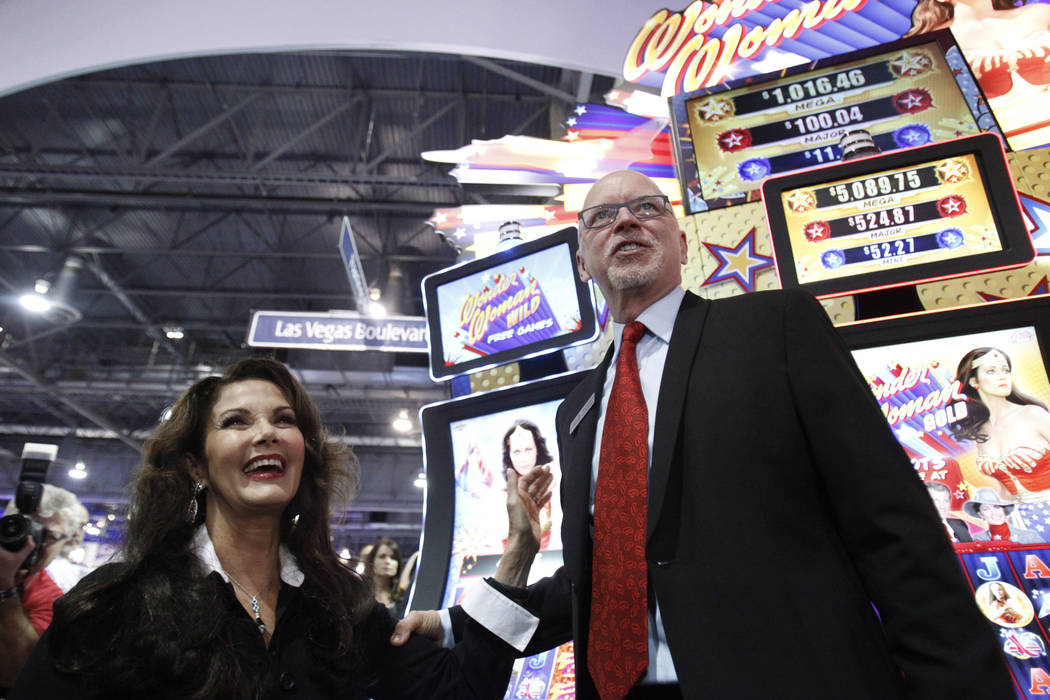 Lynda Carter, left, star of the TV series "Wonder Woman," and Richard Haddrill, CEO at Bally Technologies, pose for photos at the unveiling of the Bally Wonder Woman slot machine during the Global ...