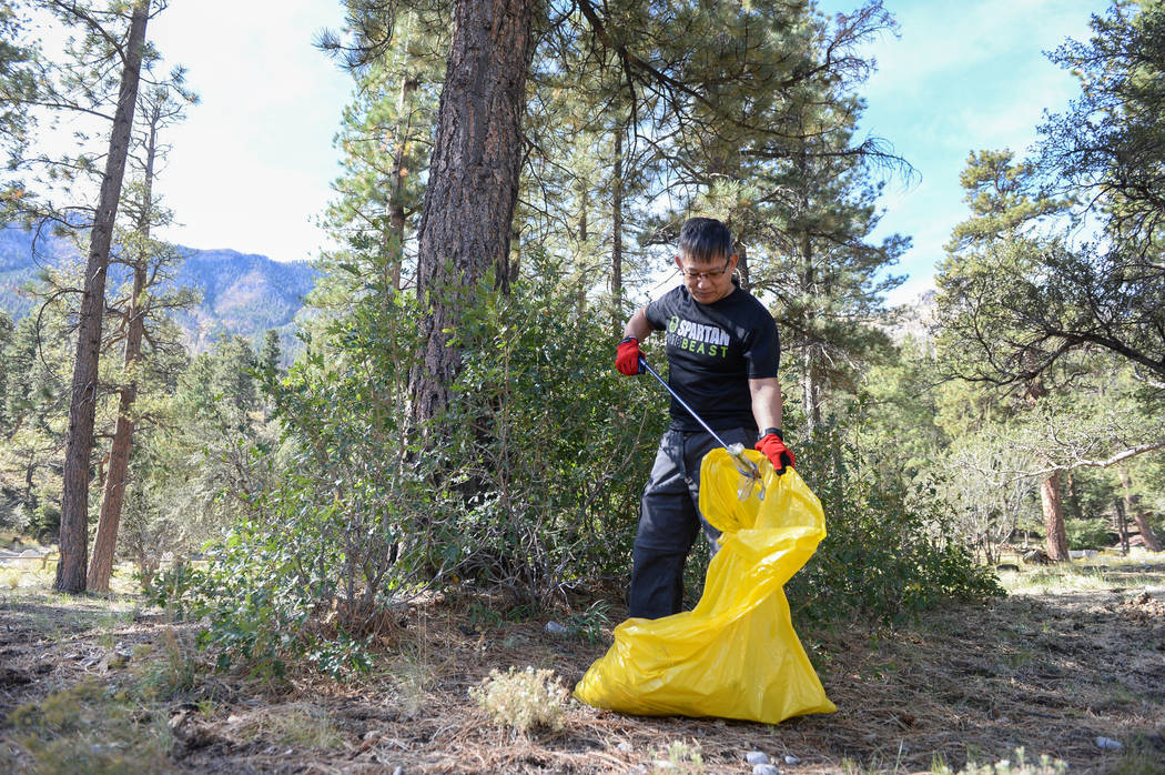 Nelson Yee of North Las Vegas places a piece of trash into a garbage bag while participating in the litter collection as a part of the volunteer program called "Green the Mountain" put o ...