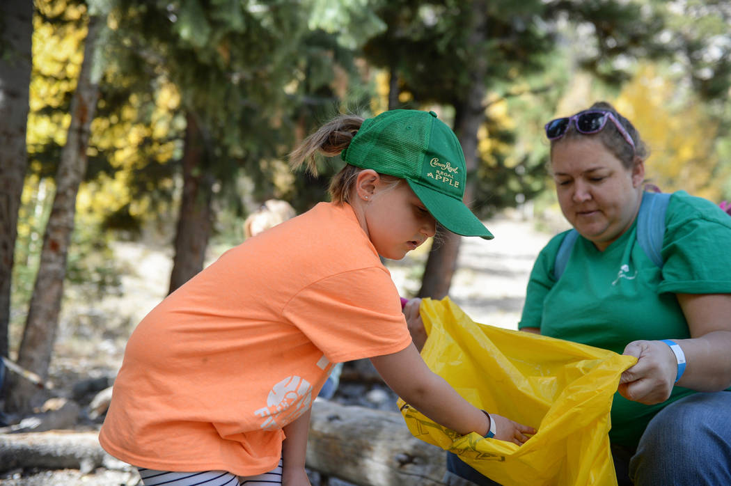 Jessica Harris, 7, from Girl Scout Troop 518, left, places a piece of trash into a garbage bag held by Stephanie Russell, while participating in the litter collection as a part of the volunteer pr ...