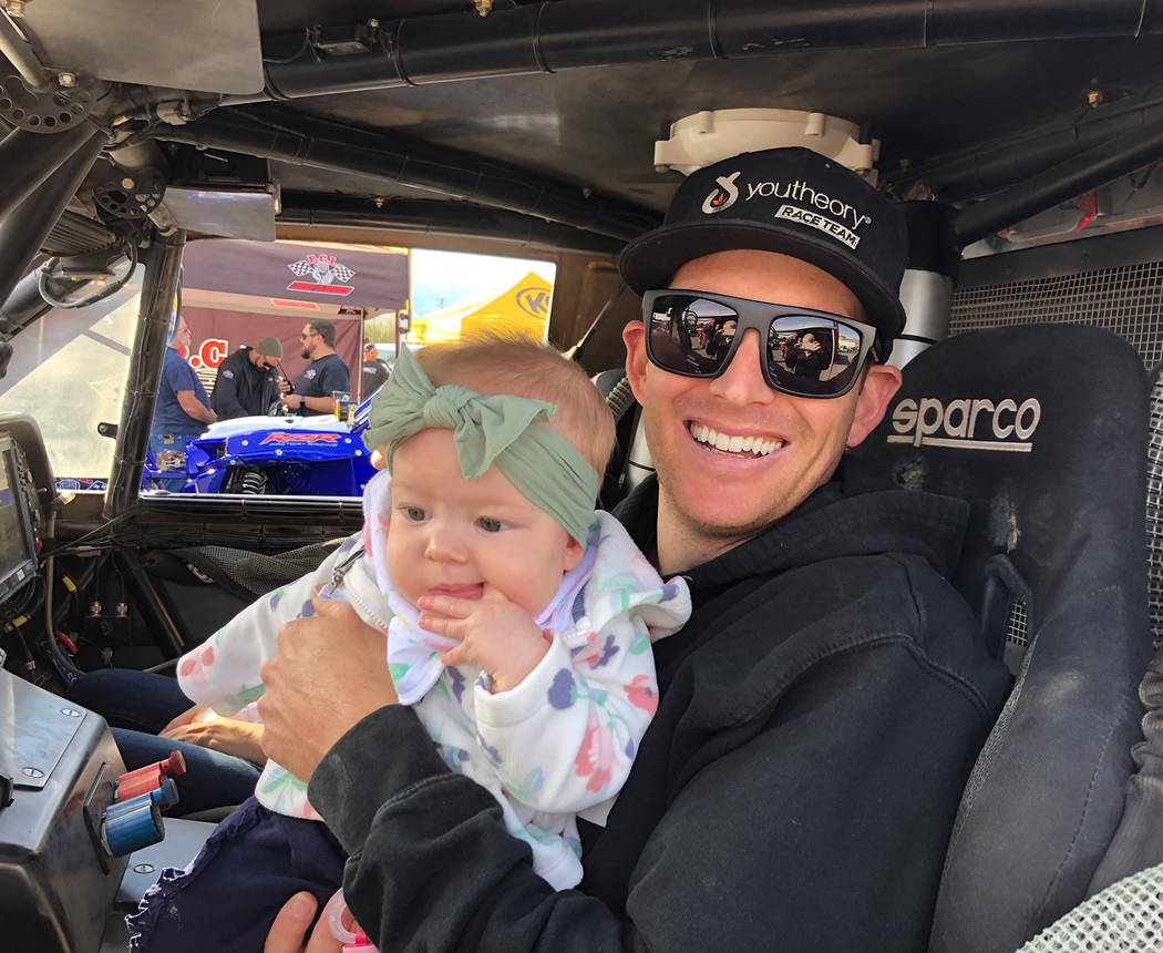 Tom Rysinski/Pahrump Valley Times Trick Truck driver Anthony Terzo of Irvine, California, sits Friday with his 6-month-old daughter Masyn while waiting for a technical inspection of his vehicle fo ...
