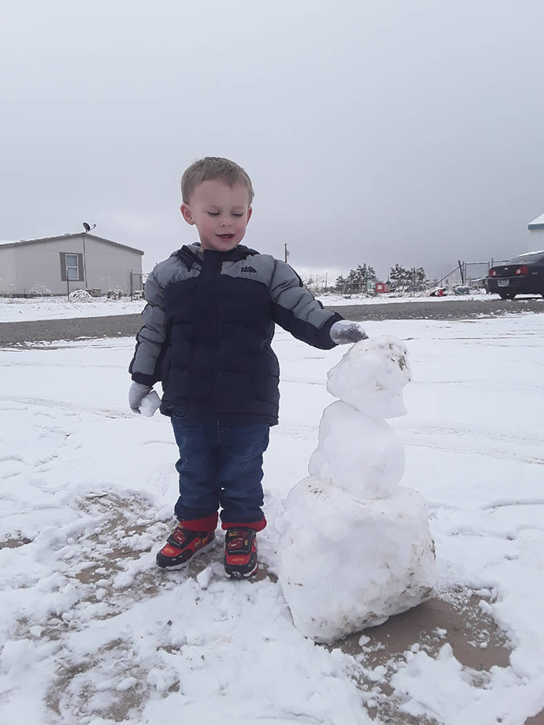 Selwyn Harris/Pahrump Valley Times Taylor Blankenship, 2, admires a snowman he and his father Tyler Blankenship created from Thursday's snowfall on the south end of the Pahrump Valley. The Nationa ...