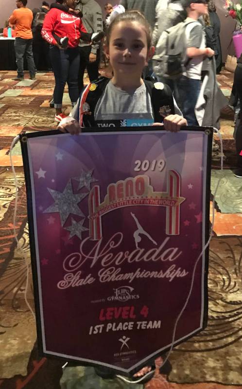 Melissa Plant/Special to the Pahrump Valley Times Arianna Plant holds the banner her Gymcats team earned for finishing in first place at the Nevada State Gymnastics Championships last weekend in Reno.