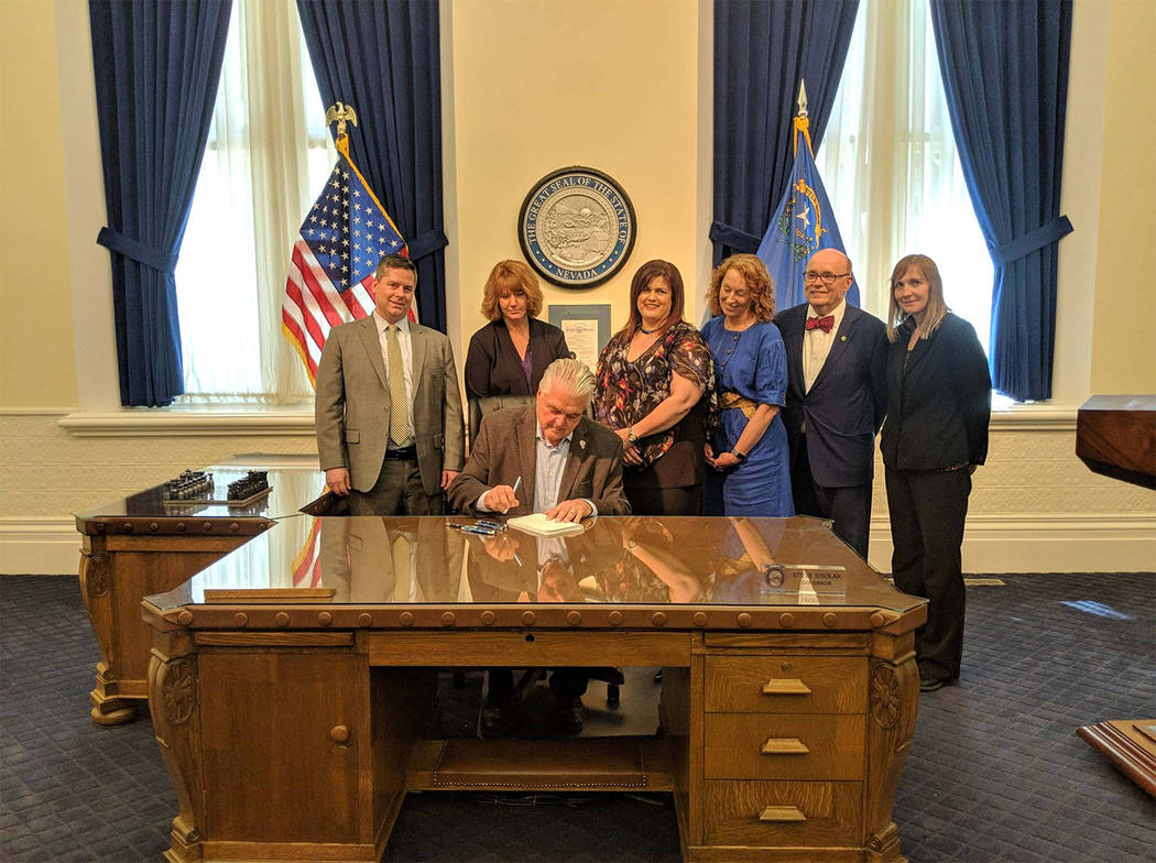 Photo courtesy of Office of the Governor Flanked by staff Nevada Governor Steve Sisolak signs t ...