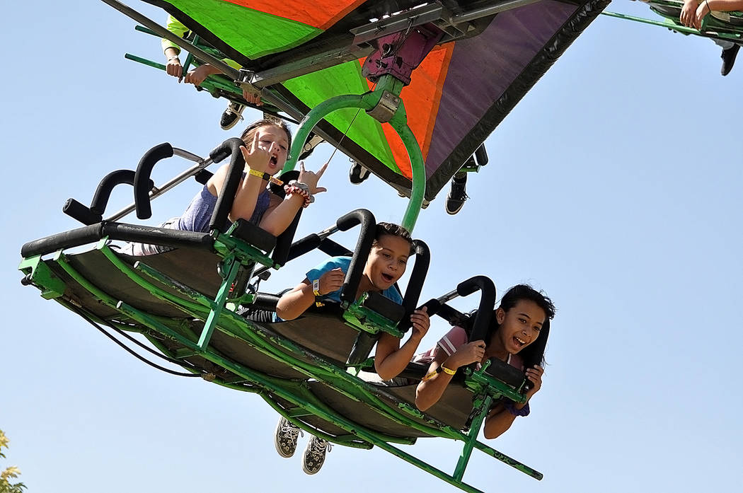 Horace Langford Jr./Pahrump Valley Times Three young individuals fly high above the carnival g ...