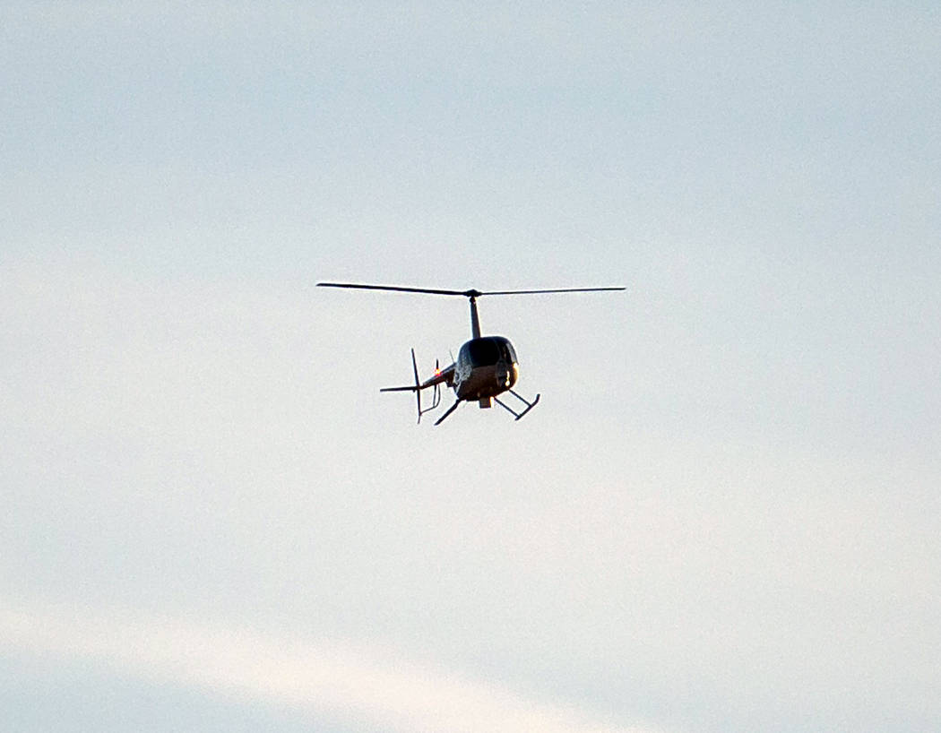 A helicopter flies above state Route 159 in response to a helicopter crash in the Red Rock Cons ...