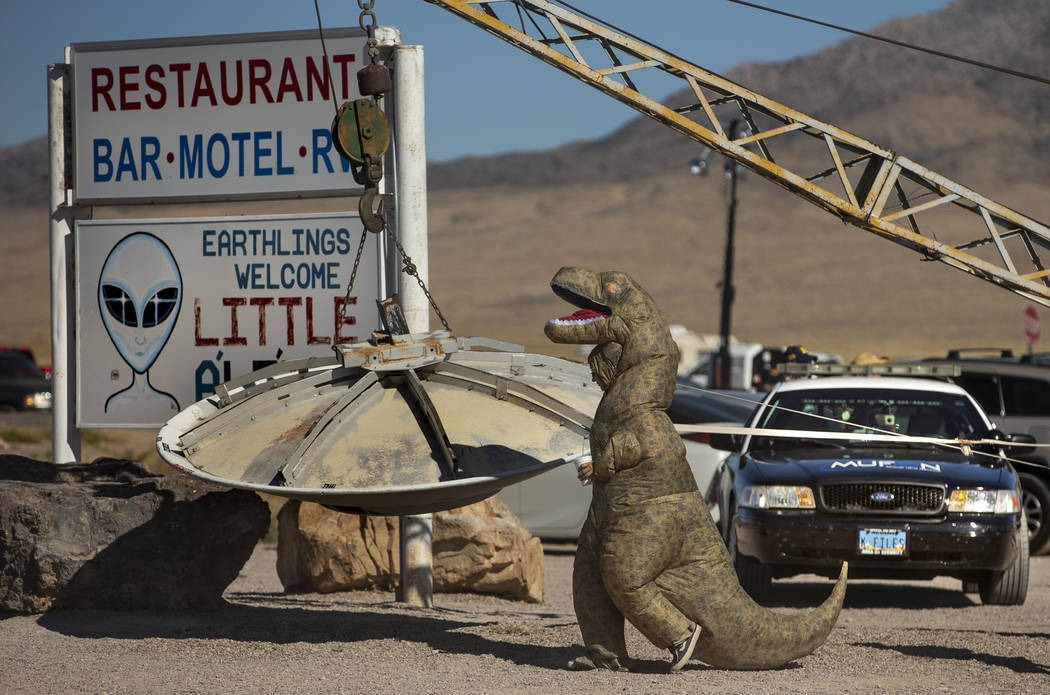 A T-Rex costumed festivalgoer walks over to the flying saucer outside the Little A'Le'Inn durin ...