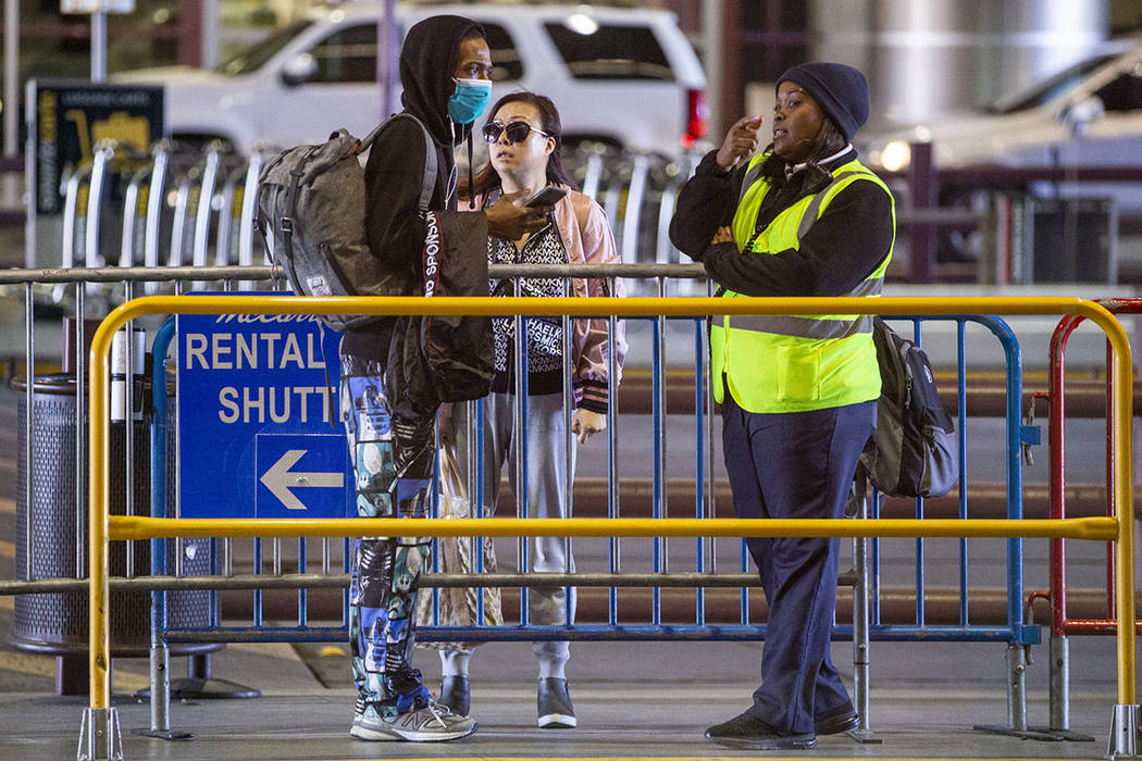A passenger wears a face mask while asking for directions outside the Terminal 1 baggage claim ...