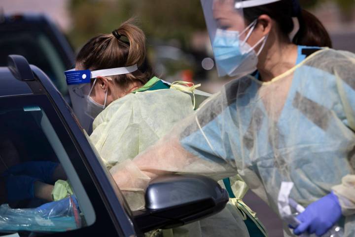 Ellen Schmidt/Las Vegas Review-Journal One volunteer swabs a patient's nose as another places i ...