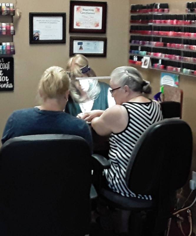 Selwyn Harris/Pahrump Valley Times A nail technician does her work while donning a full plastic ...