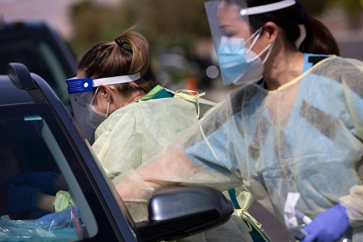 One volunteer swabs a patient's nose as another places information and a bible on their dashboa ...