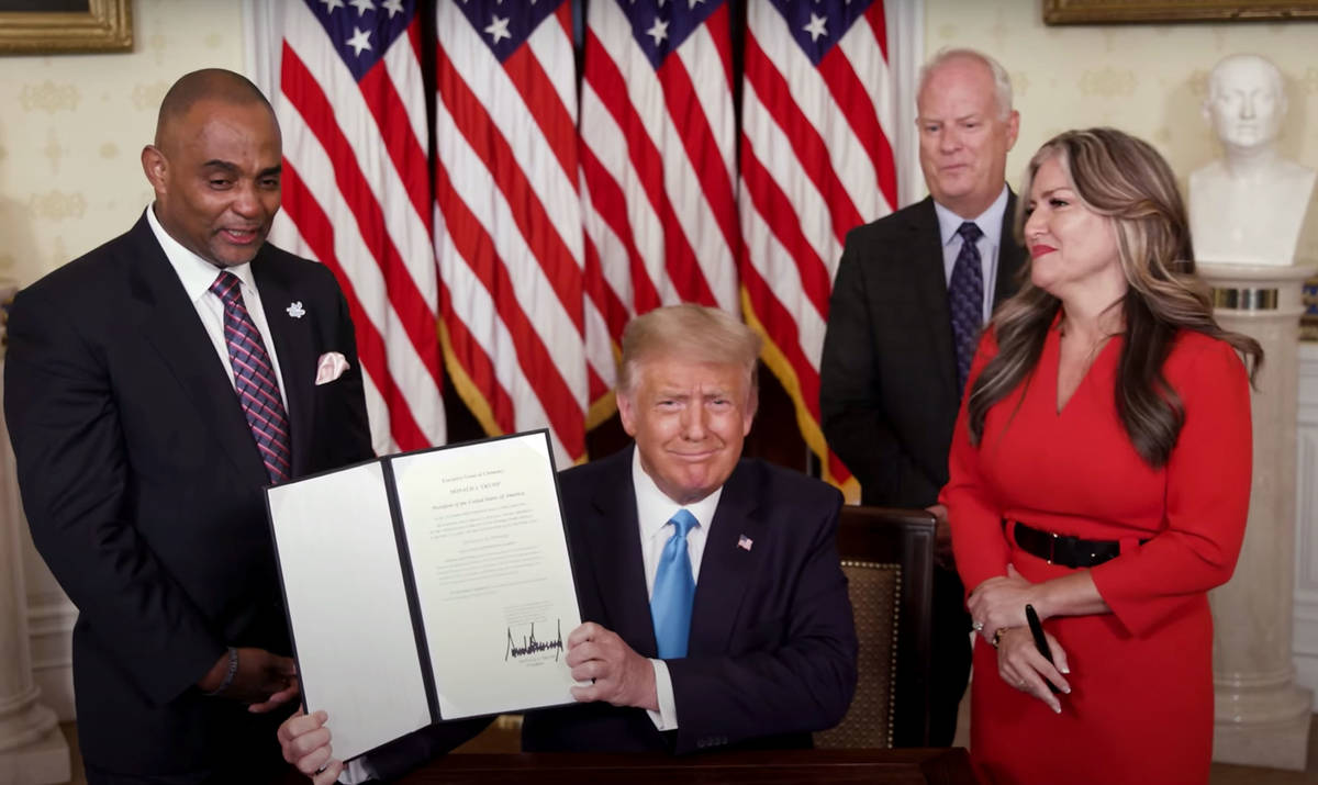 White House President Donald Trump holds up the pardon he gave Tuesday to Jon D. Ponder, left, ...