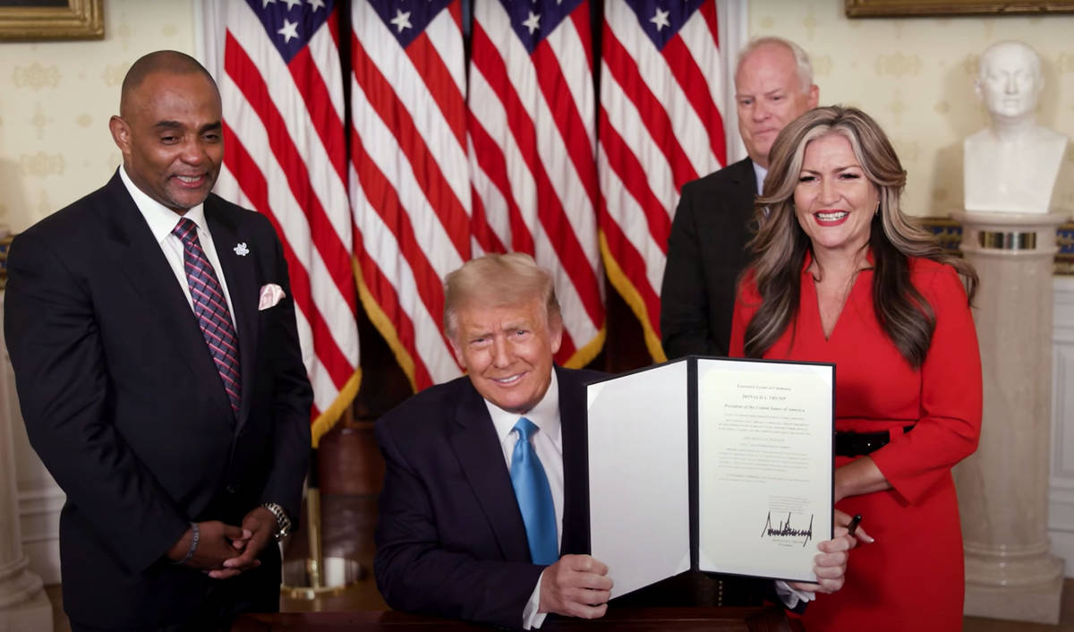 White House President Donald Trump holds up the pardon he gave Tuesday to Jon D. Ponder, left, ...