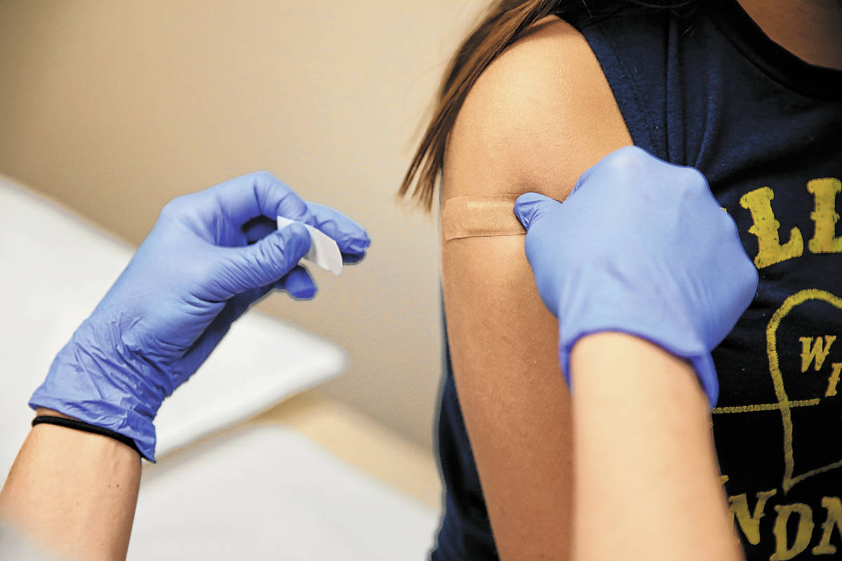 Natalia Ossa, 12, receives a vaccine from medical assistant Lindsey Johnson during a free back ...