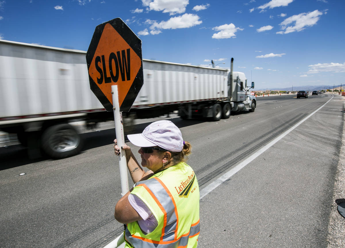 Flagger Tamey Walker directs eastbound traffic on Blue Diamond Road at Fort Apache Road on Mond ...