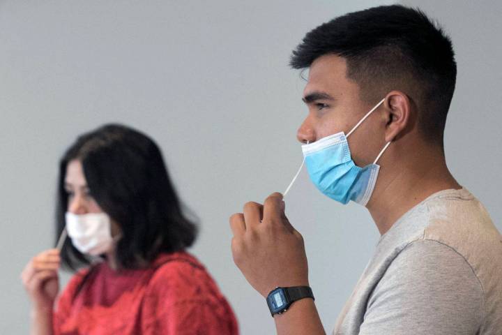 Daniel Monje, right, and Jasmine Barrett, volunteers, conduct self-swabbing test at the new COV ...