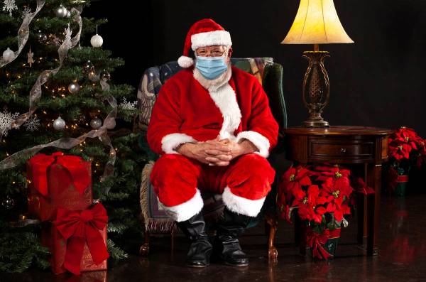 horizontal photograph of Santa Claus Sitting in a Chair Wearing a Surgical Mask and Looking Tow ...