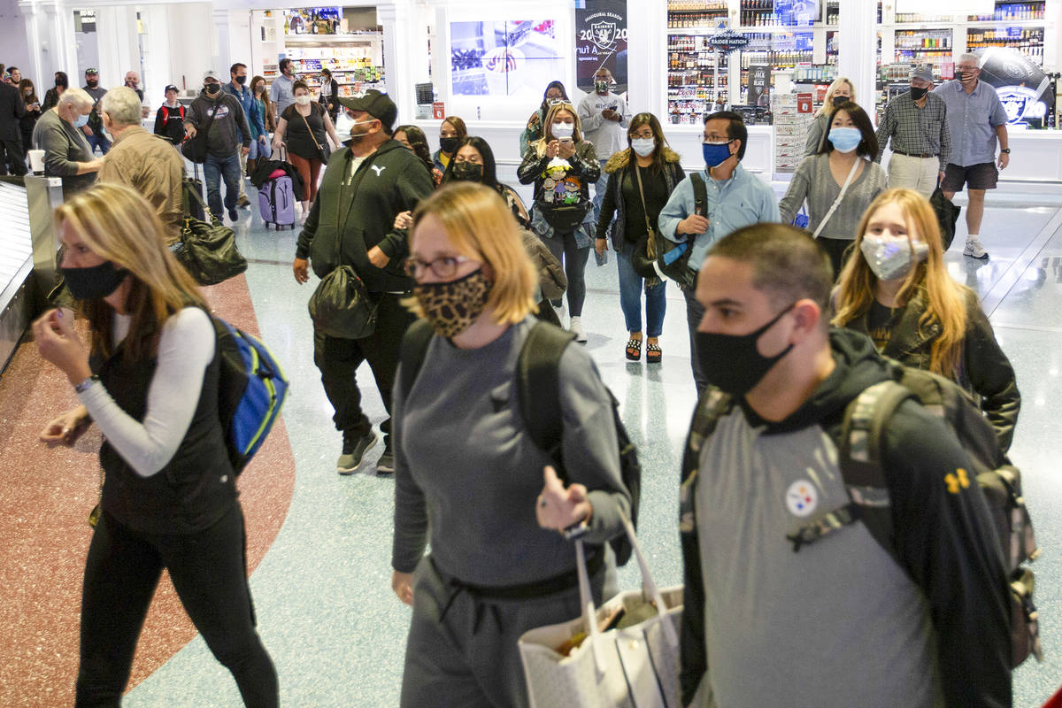 A crowd heads toward baggage claim at McCarran International Airport on Sunday, Nov. 22, 2020, ...
