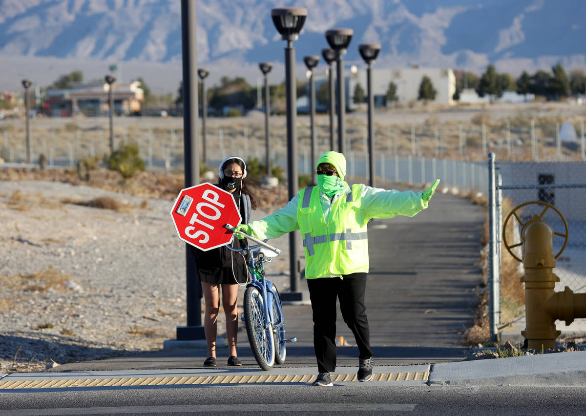 Crossing guard Mary Turner helps a Somerset Academy student at a crosswalk on Lone Mountain Roa ...