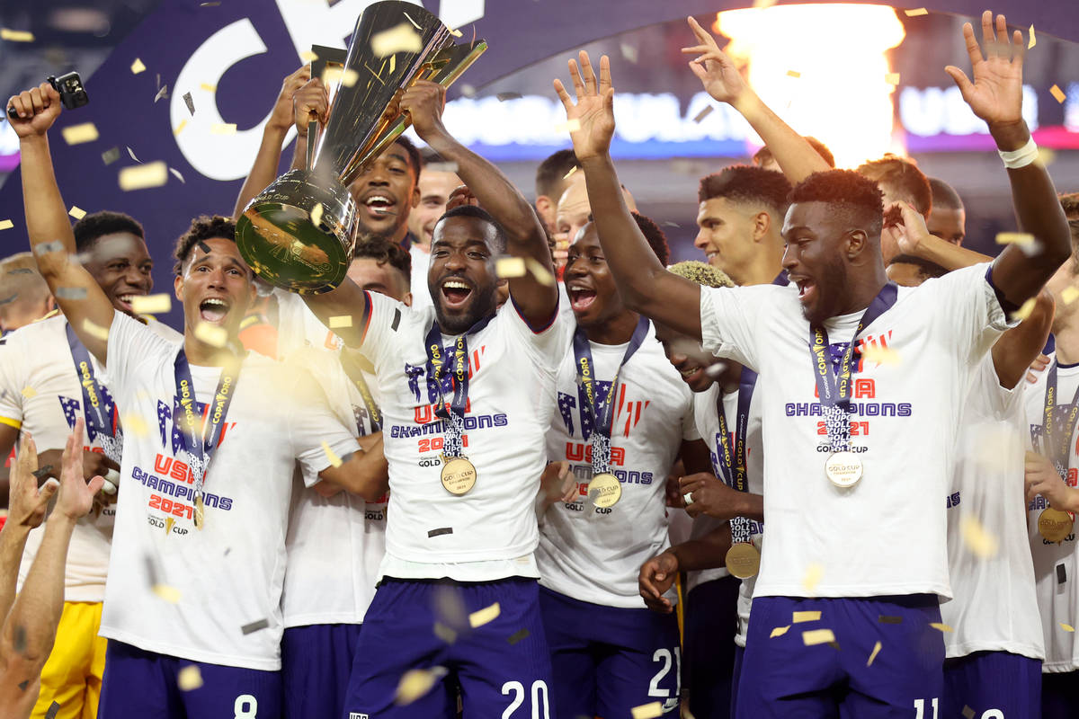 United States defender Shaq Moore (20) raises the trophy after his team's victory in the Concac ...