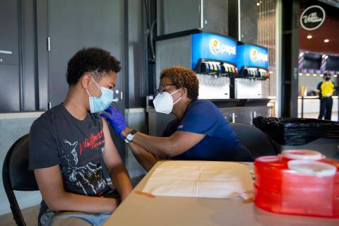 Joel Ferrell, 13, receives his first dose of the Pfizer COVID-19 vaccination from nurse Essie W ...