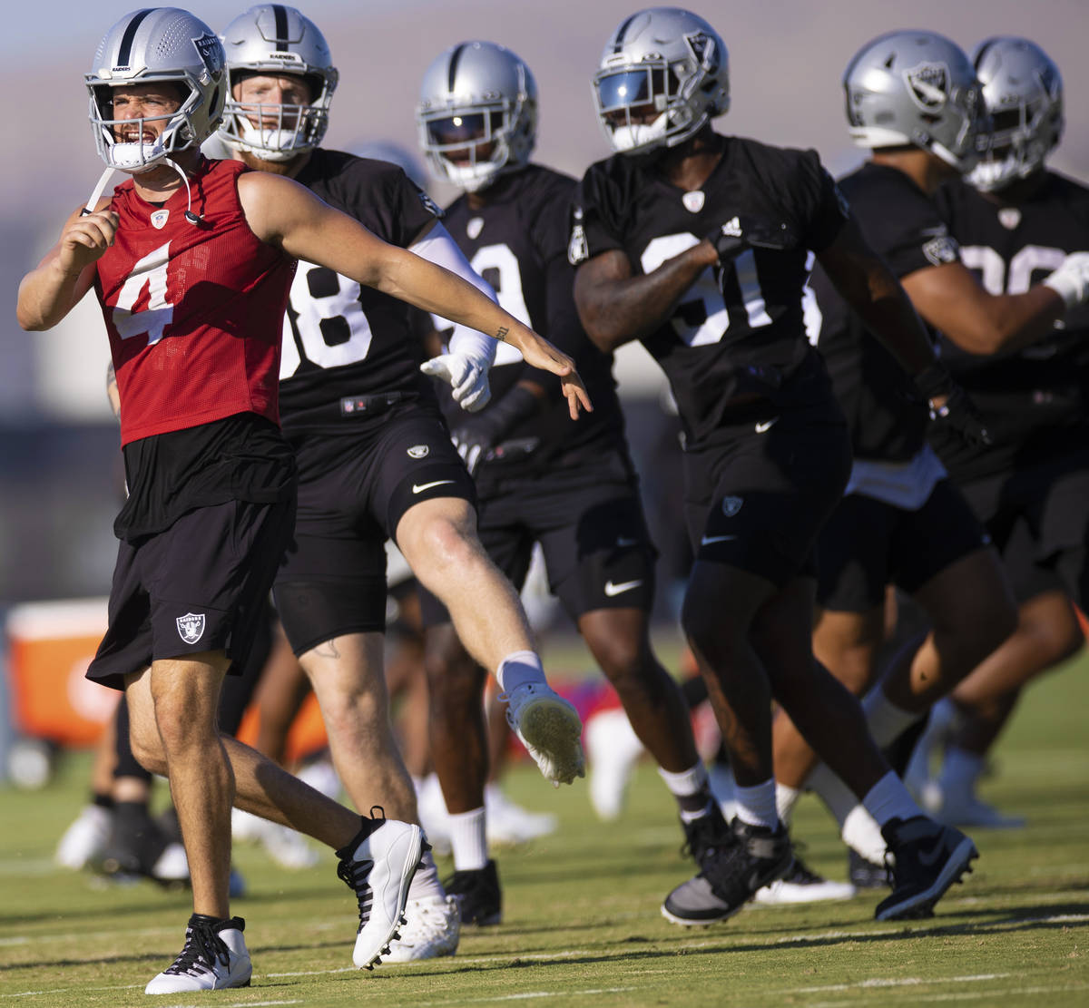 Raiders quarterback Derek Carr (4) warms up with teammates during training camp on Monday, Aug. ...