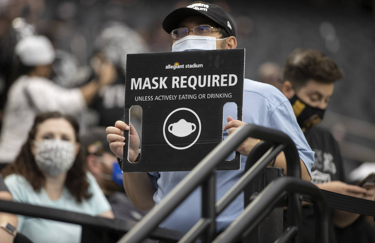 An usher holds a sign directing fans to wear masks during a special training camp practice on S ...