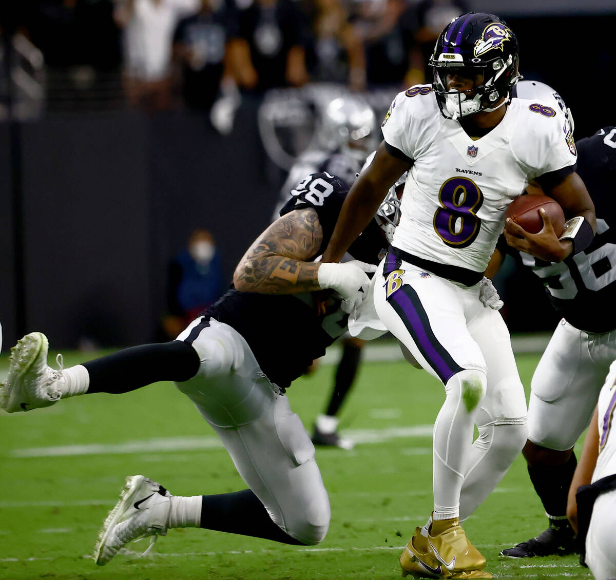 Raiders defensive end Maxx Crosby (98) tries to stop Baltimore Ravens quarterback Lamar Jackson ...