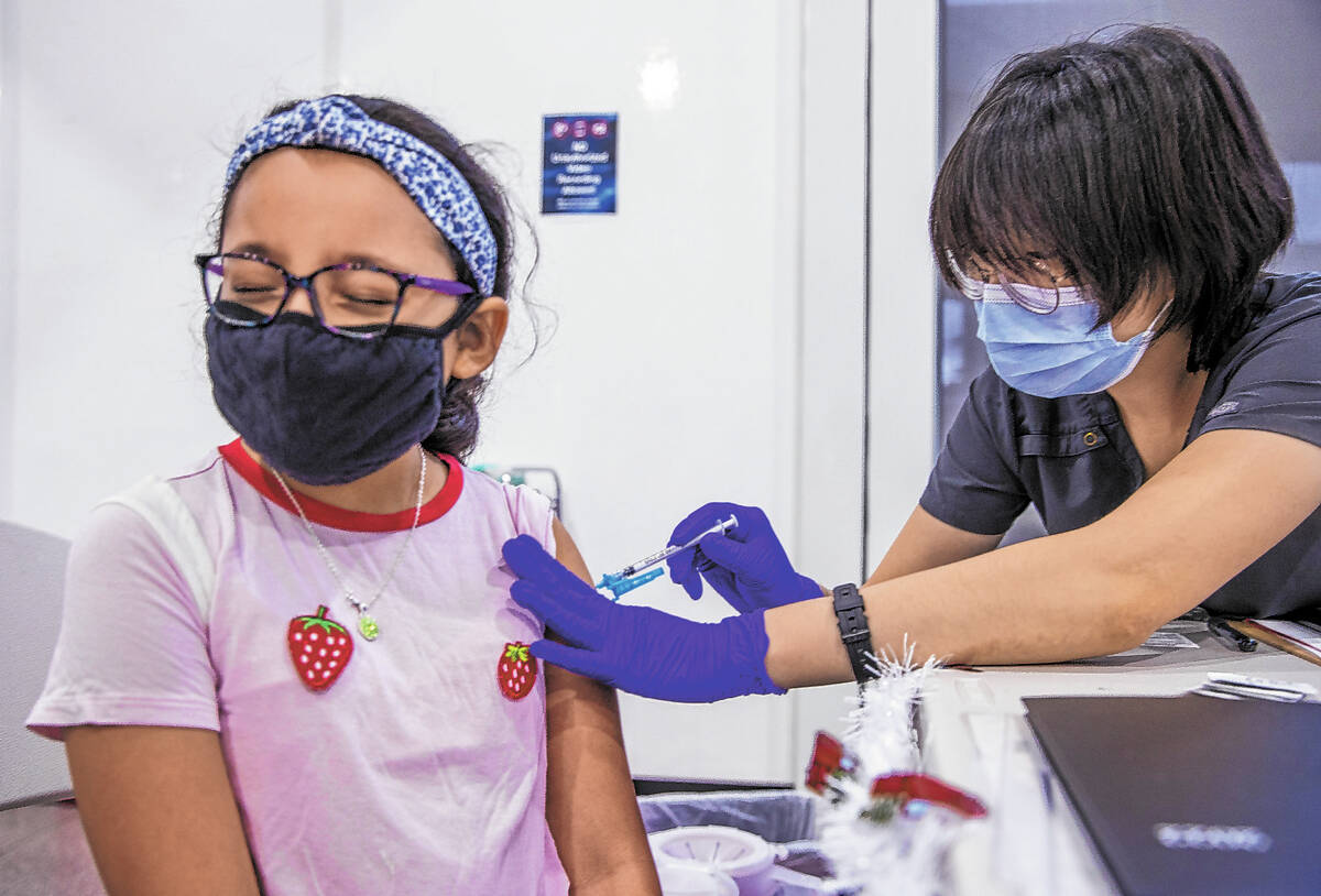 Noemi Flores Perez, 9, closes her eyes as Grisly Guerrero gives her a shot in the COVID-19 vacc ...