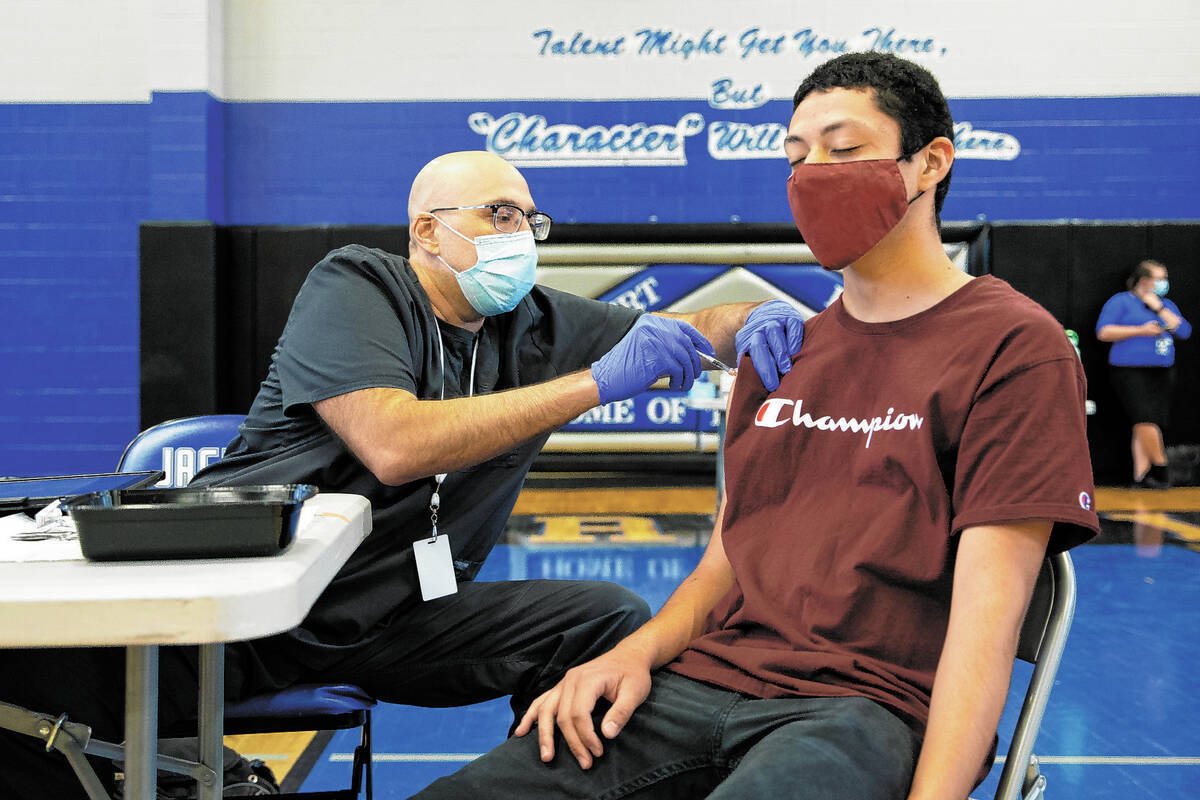 Nurse Christian Hyderkhan administers the Pfizer COVID-19 vaccine to high school senior Edwin G ...