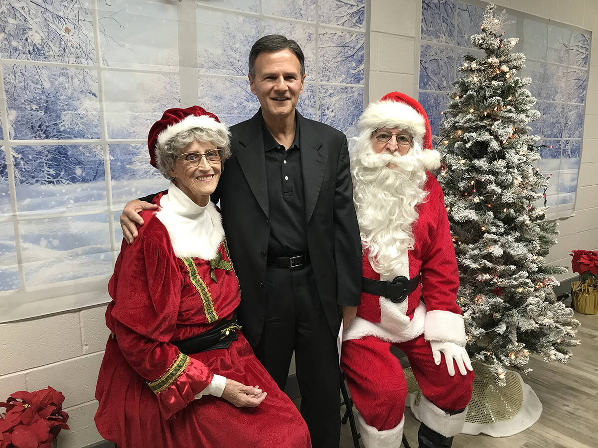 Robin Hebrock/Pahrump Valley Times Deacon Rick Minch poses with Santa and Mrs. Claus, played by ...