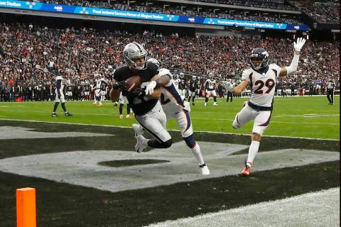 Raiders wide receiver Hunter Renfrow (13) scores a touchdown under pressure from Denver Broncos ...