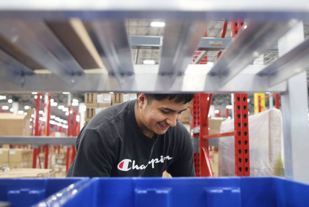 Warehouse associate assistant Enrique Roman prepares individual products to be sorted at the Se ...
