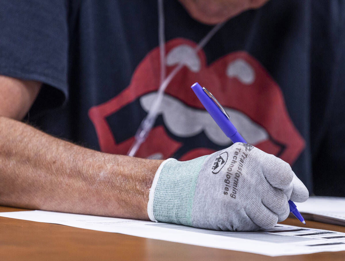 A volunteer wears Transforming Technologies gloves to shield from graphite markings on ballots, ...