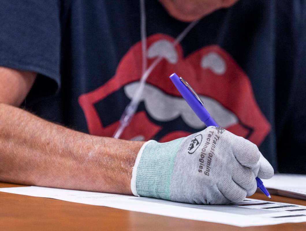 A volunteer wears Transforming Technologies gloves to shield from graphite markings on ballots, ...