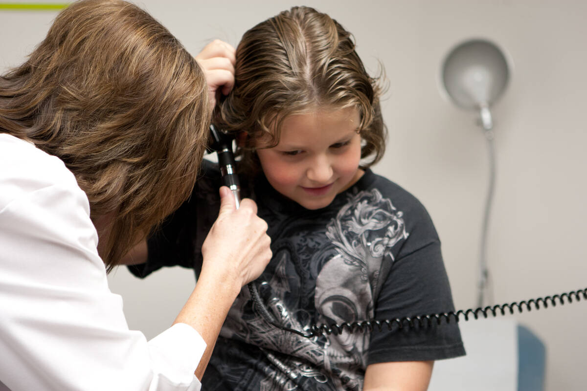 FILE - Pediatric nurse practitioner Deborah Noll checks 7-year-old Ashton Riblett's ears during ...