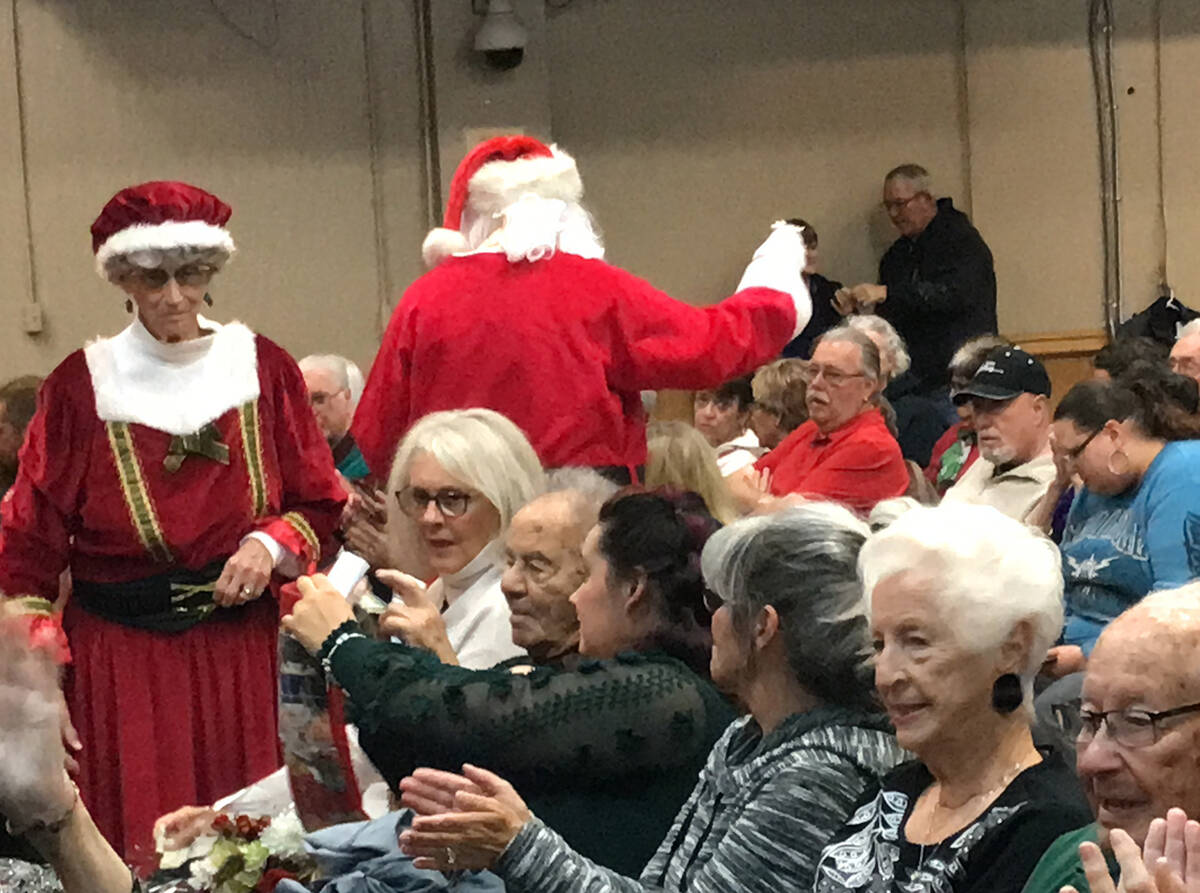 Robin Hebrock/Pahrump Valley Times Mr. and Mrs. Claus pass around stockings for Christmas benef ...