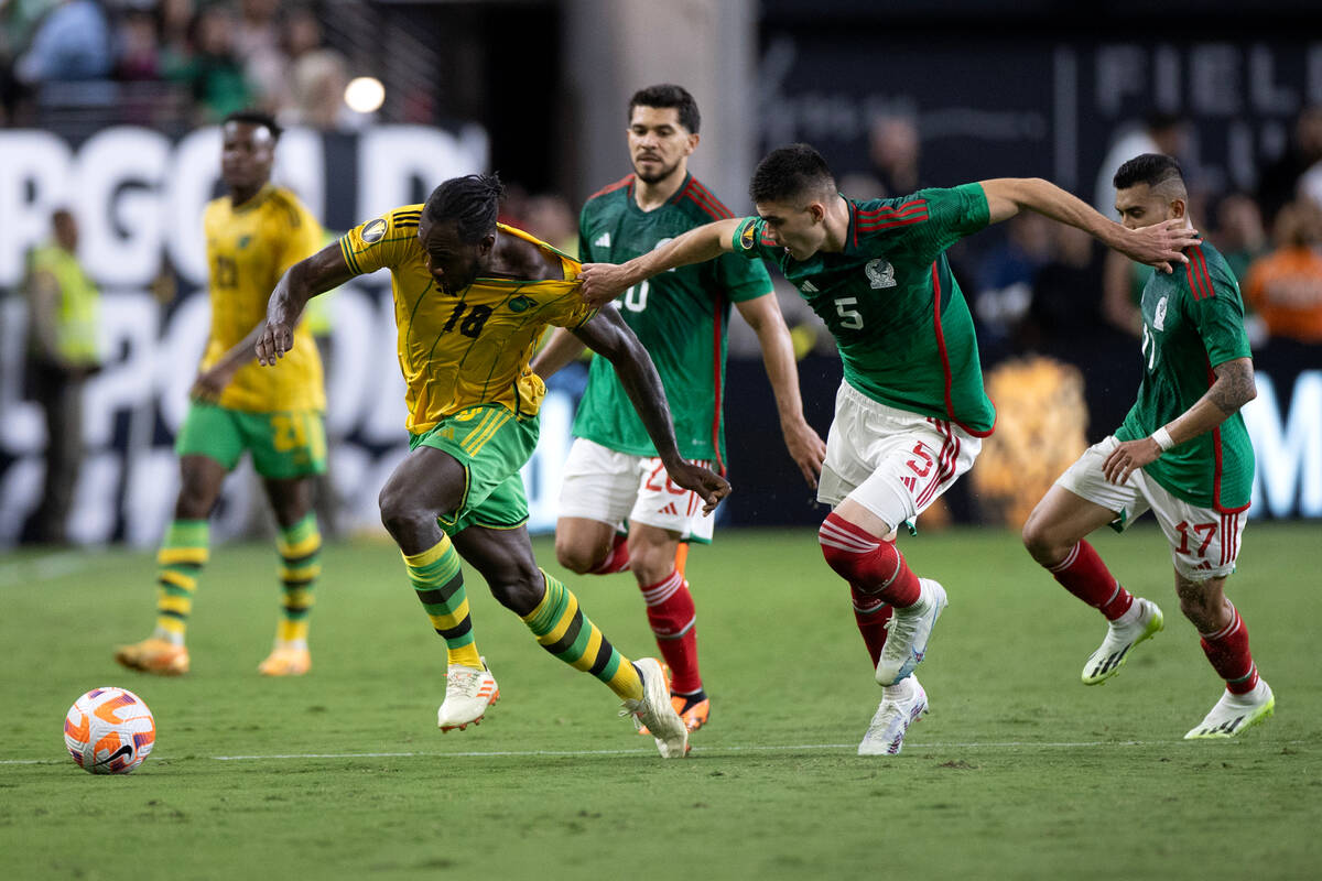 Mexico defender Johan Vásquez (5) grabs the jersey of Jamaica forward Michail Antonio (18) ...