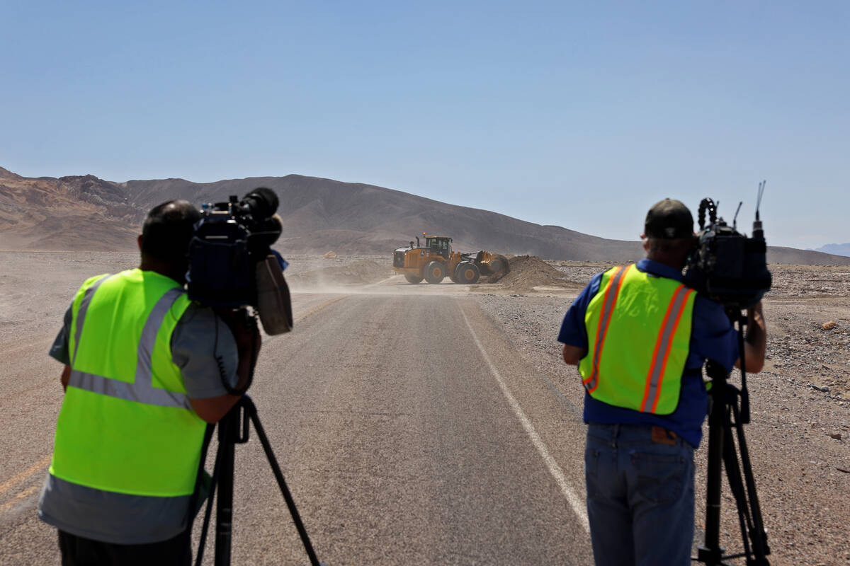 A front-end loader clears dirt from Hilary on Badwater Road in Death Valley National Park in Ca ...