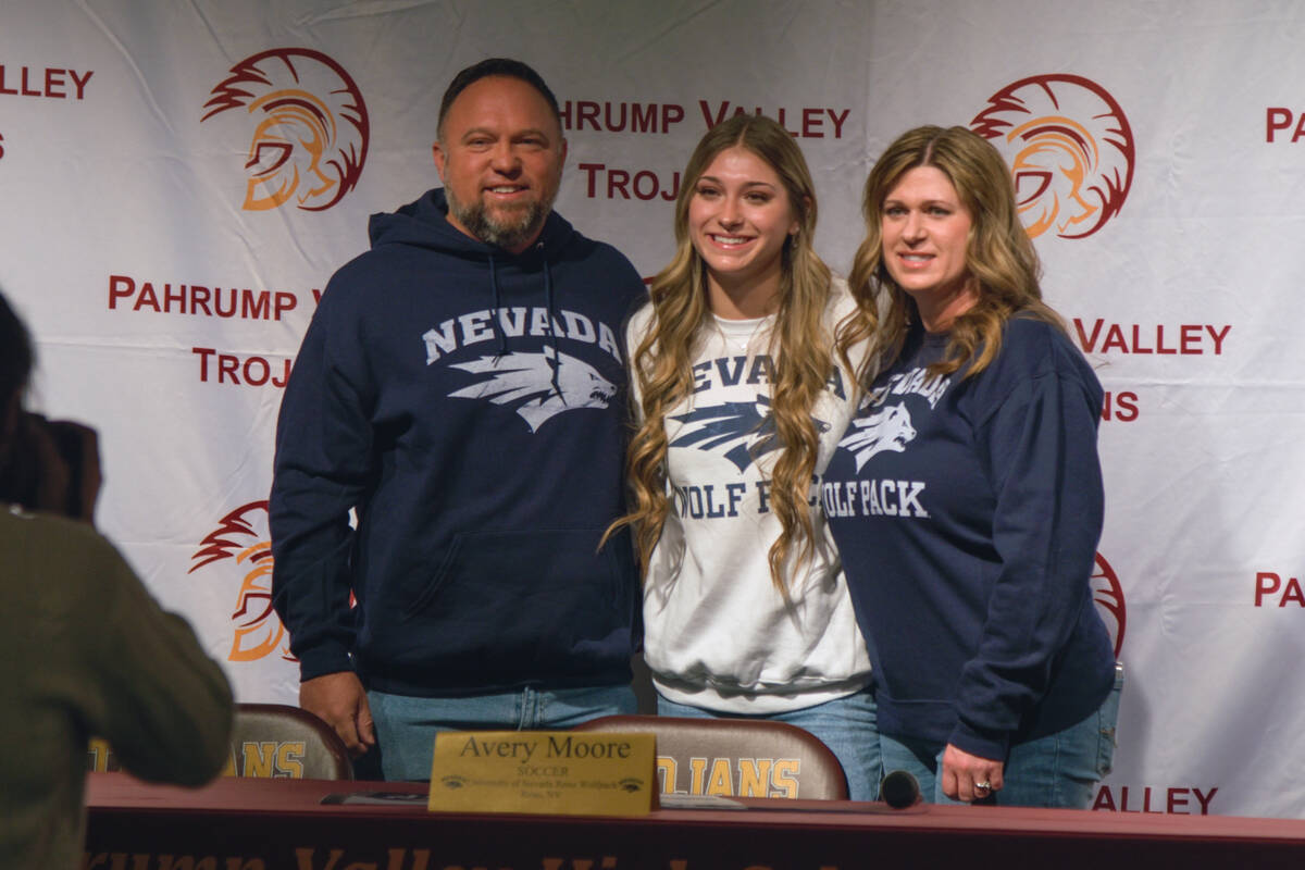 Avery Moore (center) wears her desired college school next to her mother, Charese Moore (right) ...