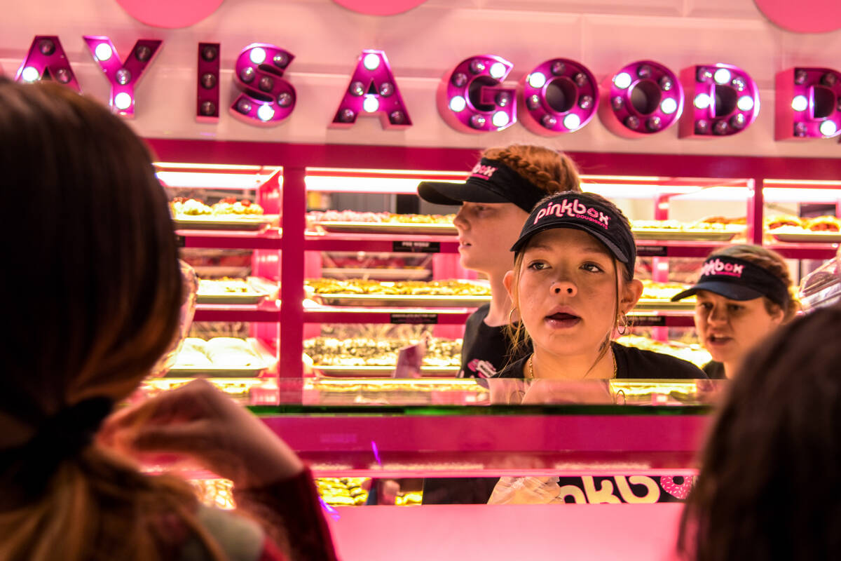 The first batch of customers are ordering at the grand opening of the Pinkbox Doughnuts shop lo ...