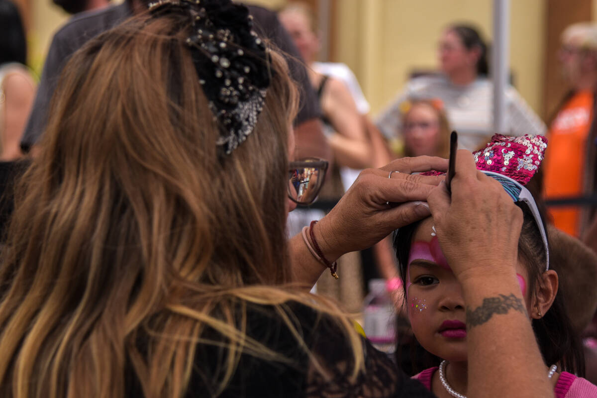 A girl is getting her face painted at the grand opening of the Pinkbox Doughnuts shop located i ...