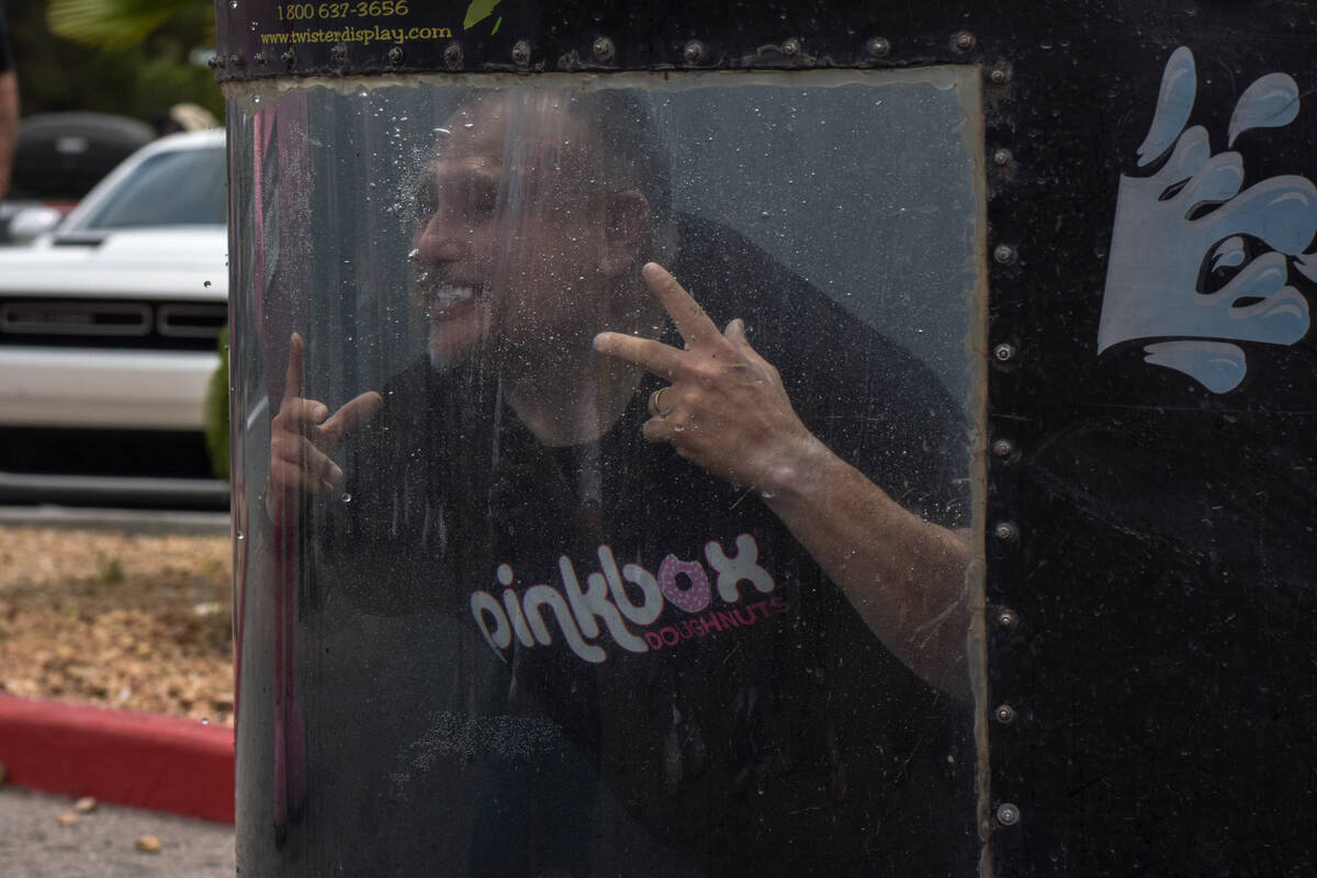 A man submerged in a dunk-tank smiles for the audience at the grand opening of the Pinkbox Doug ...