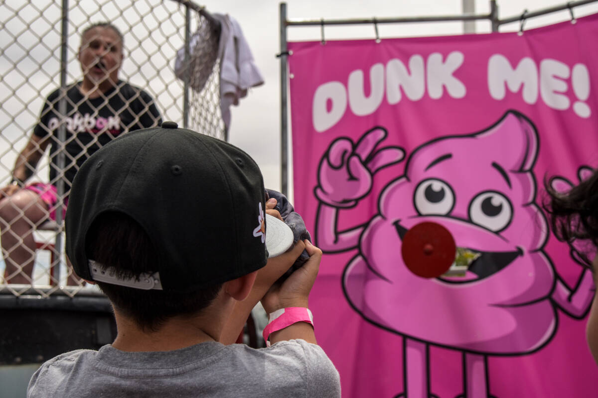 A boy concentrates to be able to dunk a man at the grand opening of the Pinkbox Doughnuts shop ...