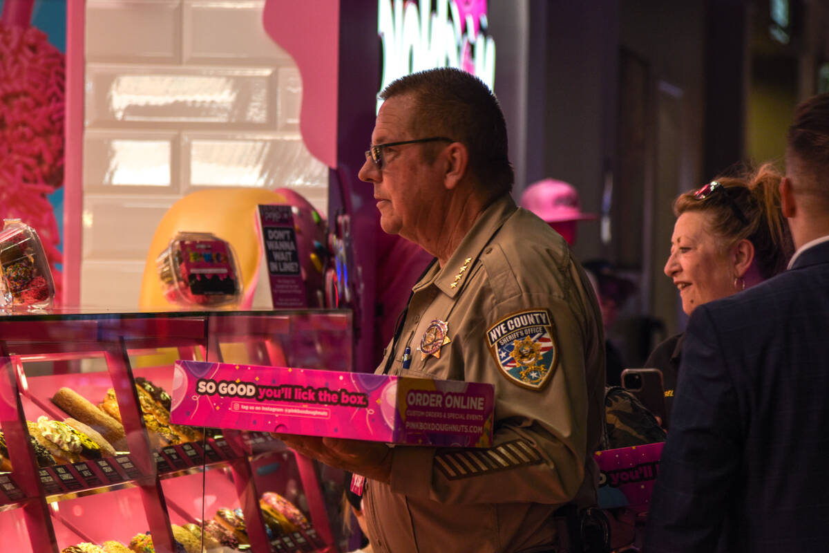 Sheriff Joe McGill holds a complimentary box of doughnuts from Pinkbox Doughnuts grand opening ...